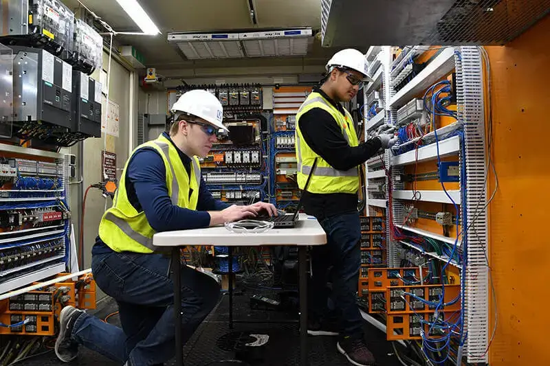 engineers performing commissioning services on control panel