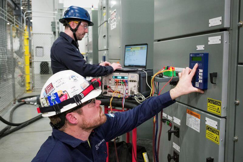 qp-testing-services technicians performing power testing on electrical panels